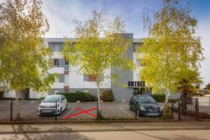 dos autos estacionados en un estacionamiento frente a un edificio en Appart cosy avec grand balcon et parking privatif en Lorient