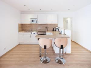 a kitchen with white cabinets and a counter with stools at city boarding lippstadt in Lippstadt