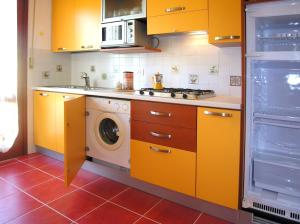 una cucina con armadi gialli e lavatrice di Appartamenti Lira a Bibione