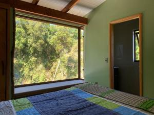 1 dormitorio con cama y ventana grande en La Rueda del Chucao en Valdivia