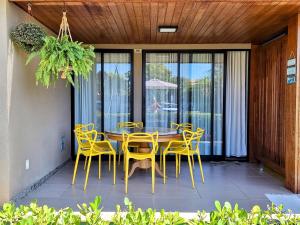 une salle à manger avec des chaises jaunes et une table dans l'établissement Itacimirim - Village na Praia da Espera, à Itacimirim