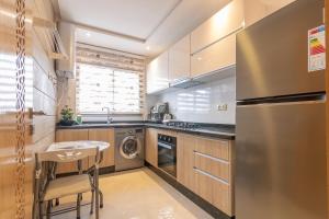 Il comprend une cuisine équipée d'un réfrigérateur en acier inoxydable et d'une table. dans l'établissement Charmant appartement près de TGV, à Kenitra