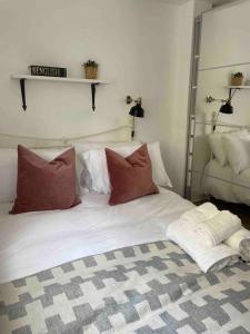 ein Bett mit roten und weißen Kissen darauf in der Unterkunft Flat in Victorian West Kensington Mansion in London