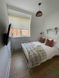 Schlafzimmer mit einem Bett mit einem Fenster und einem TV in der Unterkunft Flat in Victorian West Kensington Mansion in London