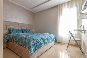 - une chambre avec un lit doté d'une couette bleue et d'une fenêtre dans l'établissement Charmant appartement près de TGV, à Kenitra