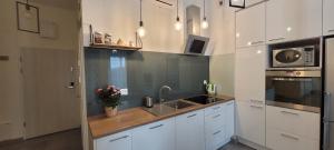 cocina con armarios blancos, fregadero y microondas en Apartament 39, en Lublin