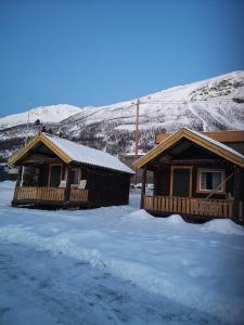 two log homes in the snow with mountains in the background at Best no1 in Manndalen