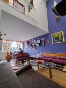 a living room with purple walls and purple couches at ZIPA HOSTEL in Zipaquirá