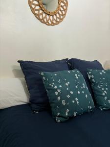 Una cama con almohadas azules y una corona en la pared. en Appartement Rubis, en Cayenne