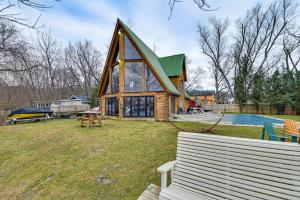a house with a green roof and a yard with two benches at Riverfront A-Frame Cabin in Troy with Pool and Dock! in Troy