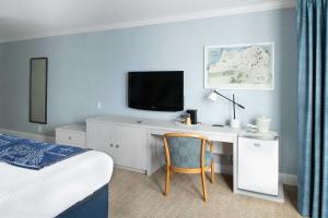 a bedroom with a desk with a television and a bed at Coventry Motor Inn in San Francisco