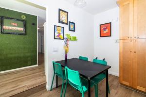 a dining room with a black table and green chairs at Colorful Home 3Bd 2Ba, Sleeps8, 1block to Univ., Pac-man, BBQ, FirePit in Redlands