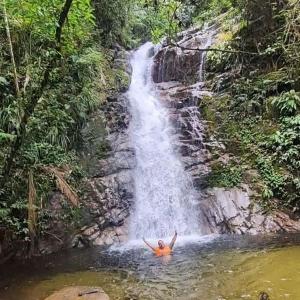 un hombre en el agua frente a una cascada en Suítes Som do Mar, en Caraguatatuba