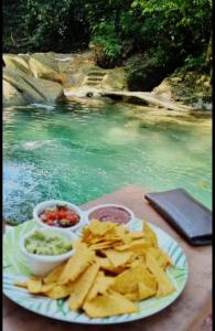 een bord chips en dip naast een zwembad met water bij Posada de Don Alonso in Puerto Barrios