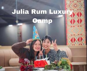 two women sitting at a table with a birthday hat at Julia Rum Luxury Camp in Wadi Rum