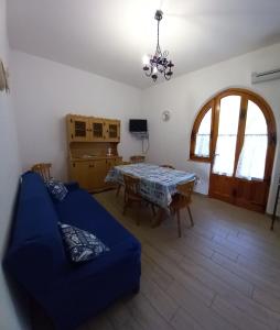 sala de estar con mesa y sofá azul en La Calla Bianca, en Torre dei Corsari
