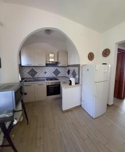 a kitchen with a white refrigerator and an archway at La Calla Bianca in Torre Dei Corsari