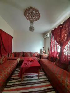 a living room with a red couch and a table at RISA FAMILY in Taroudant