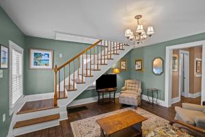 Sala de estar con escalera, sofá y TV en Historic Hartsfield House, en New Bern