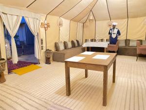 a man standing in a tent with a table at Merzouga Heart Luxury Camp in Merzouga