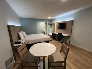 Habitación pequeña con cama, mesa y escritorio. en Travelodge by Wyndham Fairplex Pomona, en Pomona
