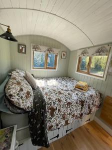 Forest View Shepherd Hut في Ewhurst: غرفة نوم مع سرير في غرفة مع نوافذ