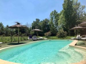 una gran piscina con sillas y sombrillas en Auberge Gardoise, en Vallérargues