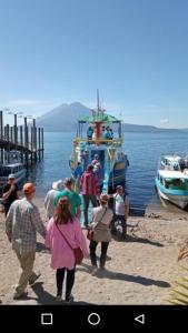 un grupo de personas caminando en un muelle cerca de un barco en Casa Zope, en Panajachel