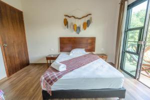 a bedroom with a bed and a large window at Casa Delfín Tulum in Macario Gomez