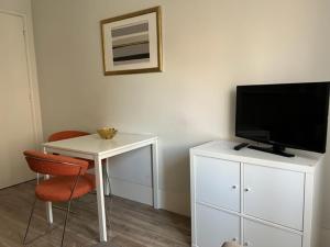 a room with a desk with a television and a table with chairs at Fantastic 1 Bedroom Apartment at Roma Avenue - 1B in Lisbon
