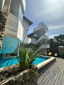 una casa con piscina al lado de un edificio en Piedras Doradas Hotel y Spa en Valeria del Mar