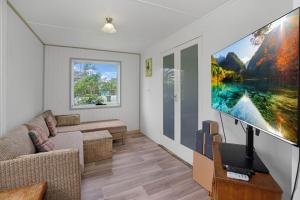 a living room with a flat screen tv on a wall at The Shack Rainbow Beach - Pets Welcome - Fully Fenced - Close to Beach in Rainbow Beach