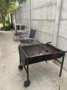 a barbecue grill with a chair and a table at Casa en colonia del sacramento in Colonia del Sacramento