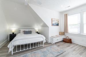 a white bedroom with a bed and a staircase at Loft on Capital - Ideally located to Distilleries in Frankfort