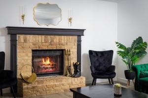 a living room with a fireplace and two chairs at Timeless-Texas-Inn - Heated Pool Oasis & Lux Vibe in Round Rock