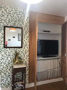 een woonkamer met een televisie en een spiegel bij Les Hortensias in Amiens