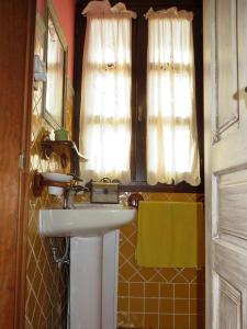 uma casa de banho com um lavatório, 2 janelas e um espelho. em Casa Pumarín em Pravia