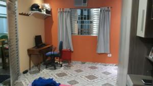 Habitación con paredes de color naranja, escritorio y espejo. en Recanto de cachoeiras en Itariri
