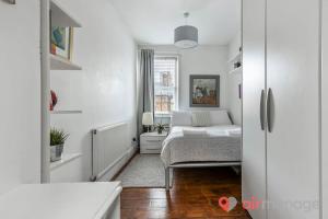 ein weißes Schlafzimmer mit einem Bett und einem Fenster in der Unterkunft West Kensington 2Bed Flat in London