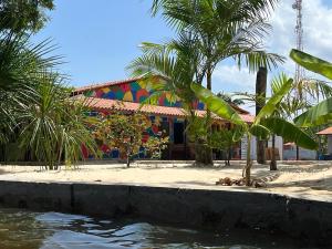 a building with a palm tree in front of the water at POUSADA PARAÍSO CULTURAL in Barreirinhas