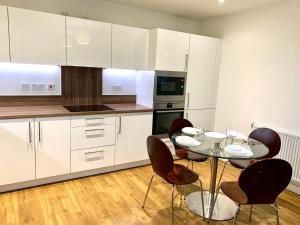 a kitchen with white cabinets and a table and chairs at Modern London Excel 2 Bedrooms 2 Bathrooms, Parking, Kitchen, Lounge, Balcony Apartment in London