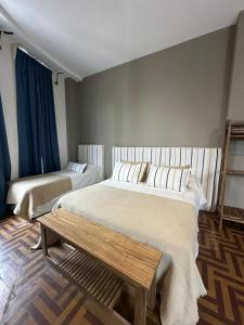 Un dormitorio con 2 camas y un banco. en Hostel New Time en Salta