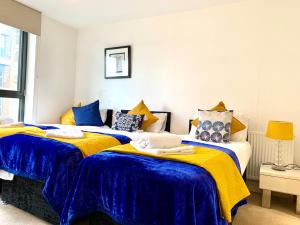 倫敦的住宿－Modern London Excel 2 Bedrooms 2 Bathrooms, Parking, Kitchen, Lounge, Balcony Apartment，卧室内的两张床,配有蓝色和黄色的床单