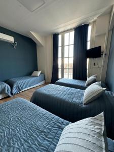 1 dormitorio con 3 camas y ventana en Hostel New Time en Salta