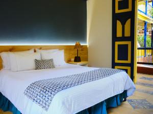 a bedroom with a bed with a blue and white comforter at Hotel Hacienda Combia in Armenia