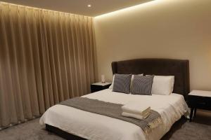 a bedroom with a large bed with white sheets and pillows at Stylish Serenity at Sunrise in Fairy Meadow +16 photos