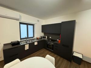 una cocina con armarios negros y fregadero en Capital Heights Suite, Victoria en Victoria