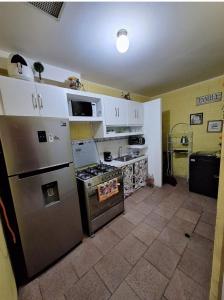 una cucina con frigorifero e piano cottura forno superiore di Casa Las Azucenas a Sonsonate