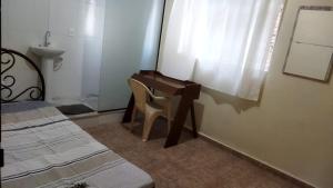 Schlafzimmer mit einem Schreibtisch, einem Stuhl und einem Waschbecken in der Unterkunft Hospedagem do Marcão in Belo Horizonte