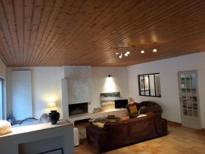 a living room with a brown couch and a wooden ceiling at Clos des Loriots in Queyrac